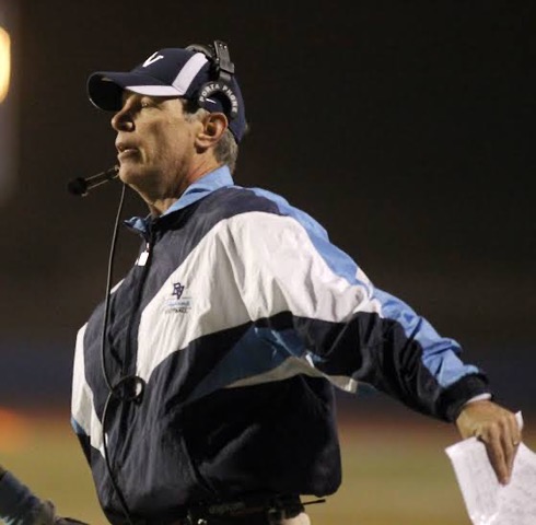 Joe Kersting on the sideline at night wearing a headset and team jacket.